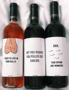 two bottles of wine sitting on top of a white bed next to each other with funny labels