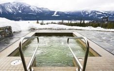 an outdoor hot tub surrounded by snow covered mountains