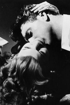 an old black and white photo of a man kissing a woman's head with her eyes closed