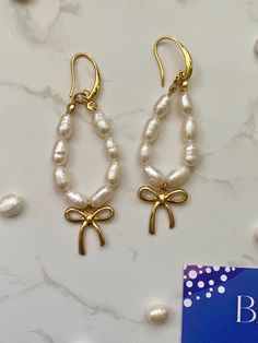 Want to embrace your inner ballerina, wear coquette inspired jewelry? These pearl bow drop gold hoop earrings will hit the mark. They are also completely PVD, which means they are water-proof, sweat-proof and tarnish-proof.   Attached to the waterproof gold drop earrings are natural freshwater pearls, hand strung in a oval fashion, giving the earrings a dreamy feel.  A beautiful gift for Christmas, a birthday, or maybe just as a treat for yourself, because as I like to say, 'a gift for me, is a Pearl Drop Earrings Gold, Pearl Bow, Bow Earrings, Inspired Jewelry, Sweat Proof, Drop Earring, Gold Drop Earrings, Jewelry Earrings Hoops, Pearl Drop Earrings