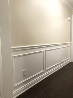 an empty room with white paneling and wood floors