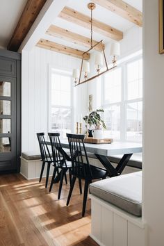 a dining room table with four chairs and a bench in front of the window,