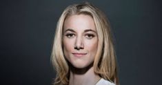 a woman with blonde hair is posing for a photo in front of a black background