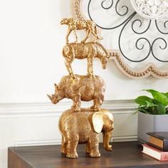 two golden elephants on top of each other in front of a mirror and bookshelf