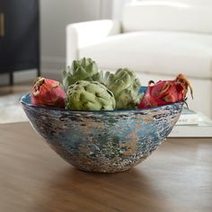 a bowl filled with flowers sitting on top of a wooden table