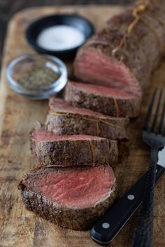 sliced steak on cutting board with knife and fork