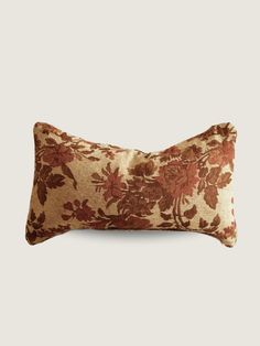 a brown and red floral pillow on a white background