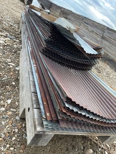 several metal sheets stacked on top of each other in front of some rocks and gravel