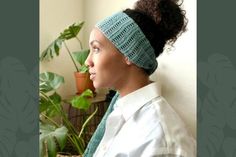 a woman wearing a knitted headband in front of a potted plant