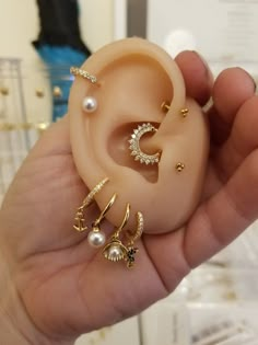 a person holding three different types of ear piercings