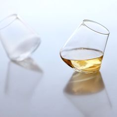 two glasses filled with liquid sitting on top of a white table next to each other