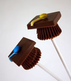 two chocolate brooms with yellow and blue pins sticking out of them on top of each other