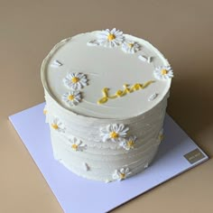 a white cake with daisies and the word love on it