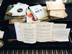 an open book sitting on top of a piano next to music sheets and other musical instruments