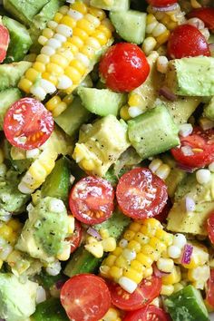 a salad with avocado, tomatoes, corn and cucumber