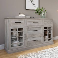 a wooden cabinet with glass doors and drawers in a living room next to a potted plant