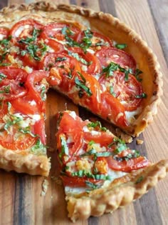 a tomato tart is cut into slices on a cutting board with one slice missing