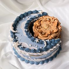 there is a blue and white cake with gold decorations on the top that looks like it has been made out of fondant