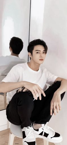 a man sitting on top of a white chair in front of a mirror wearing black and white shoes