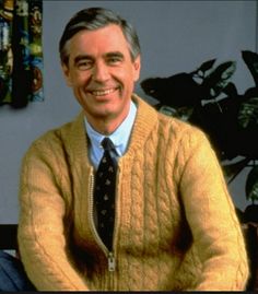 a man in a sweater and tie is smiling for the camera with a quote on it