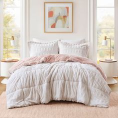 a white bed with pink comforter and pillows