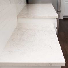 two white counter tops in a kitchen with wood flooring and tile backsplash