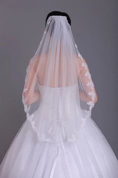 the back of a bride's wedding dress, with her veil draped over her head