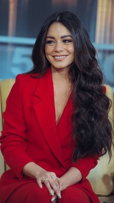 a smiling woman in a red suit sitting on a chair