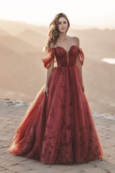 a woman in a red dress standing on top of a hill