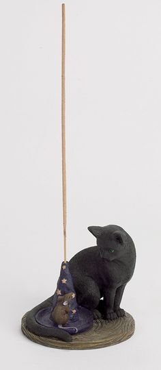 a cat figurine sitting on top of a witches hat with a broom in its mouth