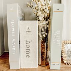 three books are sitting on a shelf next to a vase with white flowers in it