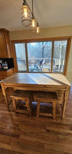 a wooden table sitting in the middle of a living room next to a kitchen window