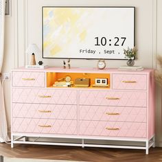 a pink dresser with gold handles and drawers in front of a large poster on the wall