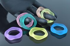 five different colored rings sitting next to each other on top of a black surface,