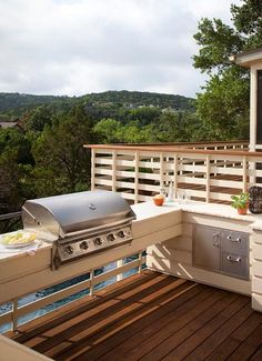 an outdoor kitchen on a deck overlooking the trees