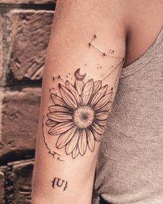 a woman's arm with a sunflower tattoo on the left side of her arm