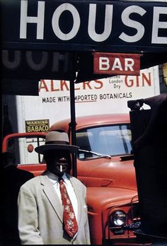 a man wearing a suit and tie standing in front of a sign for a bar