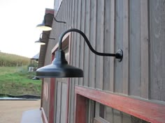 an outdoor light on the side of a building next to a door with a barn in the background