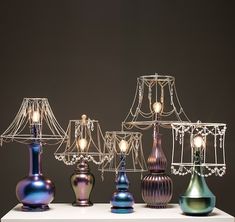 several different colored lamps sitting on top of a white table next to eachother