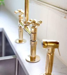 three golden faucets on a white counter top