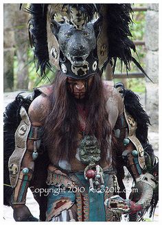 a man wearing an elaborate headdress with feathers on it's face and chest