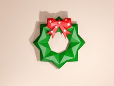 a green origami christmas wreath with red bows on the front and white stars on the back