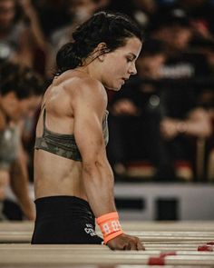 a woman kneeling down on the ground in front of an audience with her hands behind her back