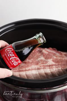 a person holding a bottle of beer in front of an open crock pot filled with raw meat