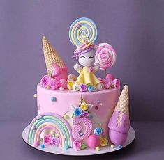 a pink cake decorated with candy, lollipops and candies on top