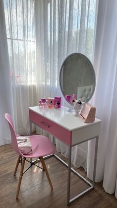 a desk with a mirror and pink chair in front of the window next to it