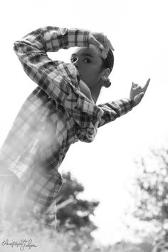 a man standing in the grass with his hands on his head and looking up at something