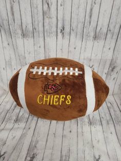 a stuffed football with the name chiefs on it sitting on a wooden table next to a wall