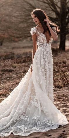 a woman in a wedding dress is walking through the woods with her back to the camera