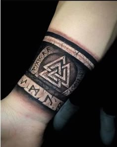 an arm with a tattoo on it that has various symbols and letters in the middle